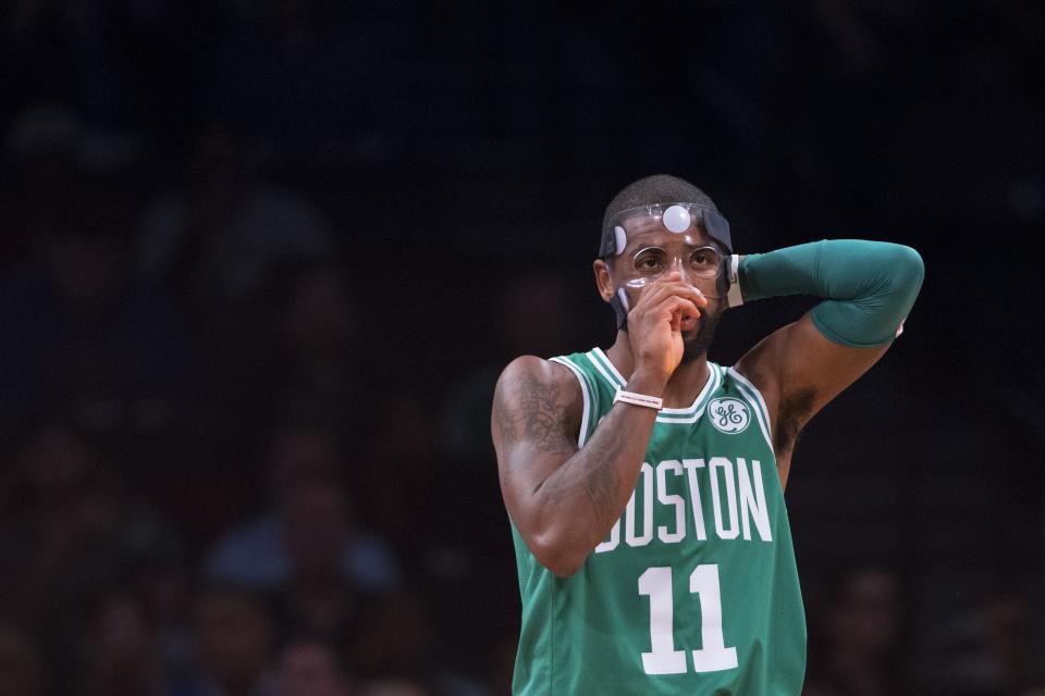 Kyrie Irving tries to get the mask protecting the broken bone in his face to sit right. It doesn’t sit right. (Getty)