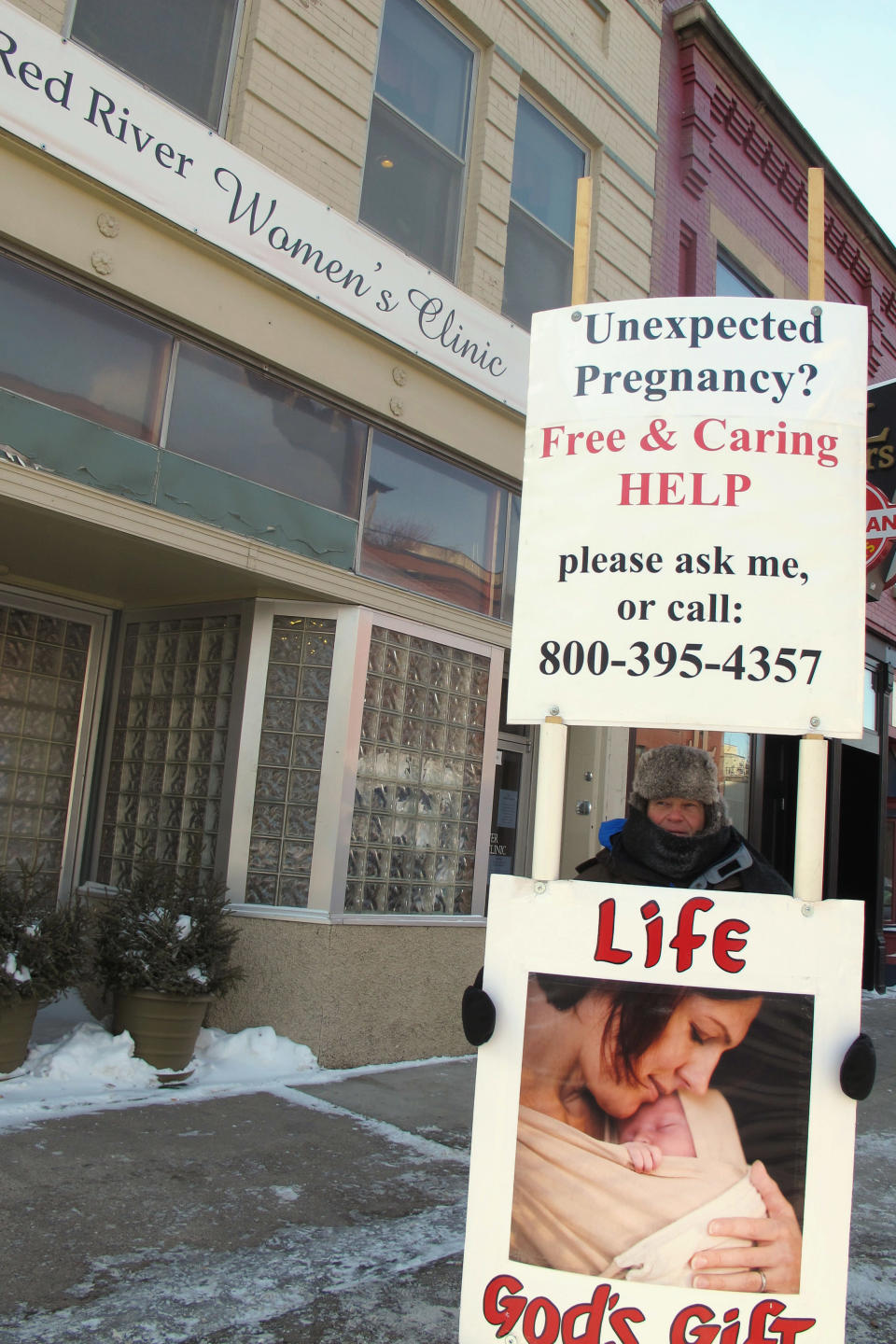 FILE - An abortion protester stands outside the Red River Valley Women's Clinic in Fargo, N.D., on Feb. 20, 2013. North Dakota's only abortion clinic filed a lawsuit Thursday, July 7, 2022, seeking to block enforcement of the state's trigger law banning abortion in the wake of the Supreme Court's reversal of Roe v. Wade. The Red River Women's Clinic argues that the state constitution protects the right to abortion. (AP Photo/Dave Kolpack, File)