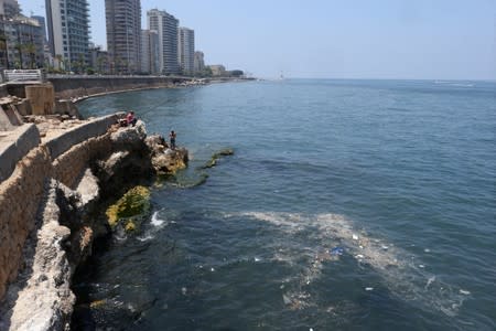 A fisherman dangles his line to catch fish in polluted water off Beirut's seaside Corniche