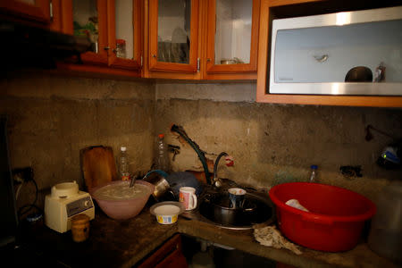 A red plastic container filled with water to wash the dishes is seen in Jenny Montana's kitchen, on the 9th floor of an apartment block in downtown Caracas, Venezuela, March 18, 2019. REUTERS/Carlos Garcia Rawlins