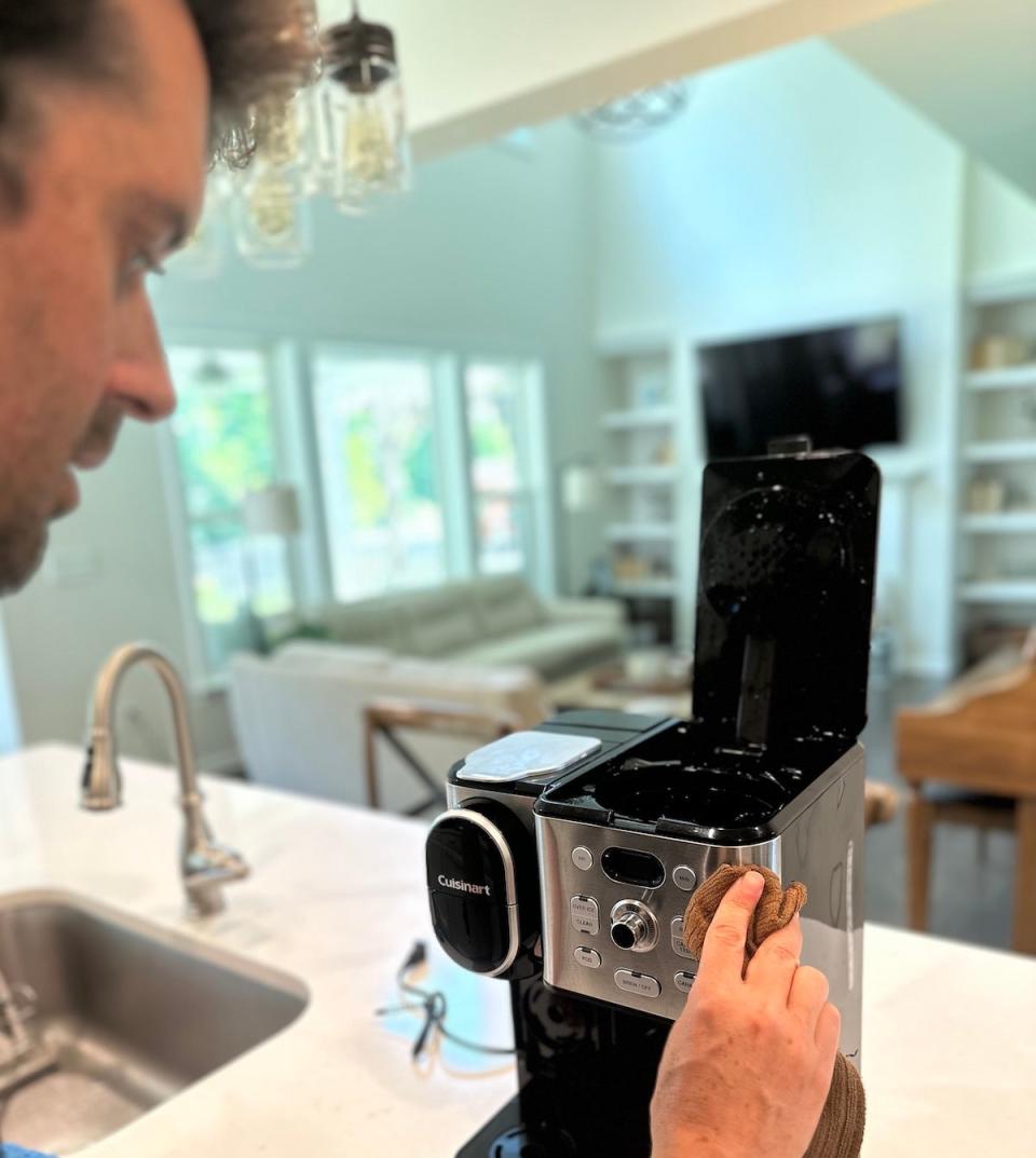 Man cleaning exterior of Cuisinart coffee maker