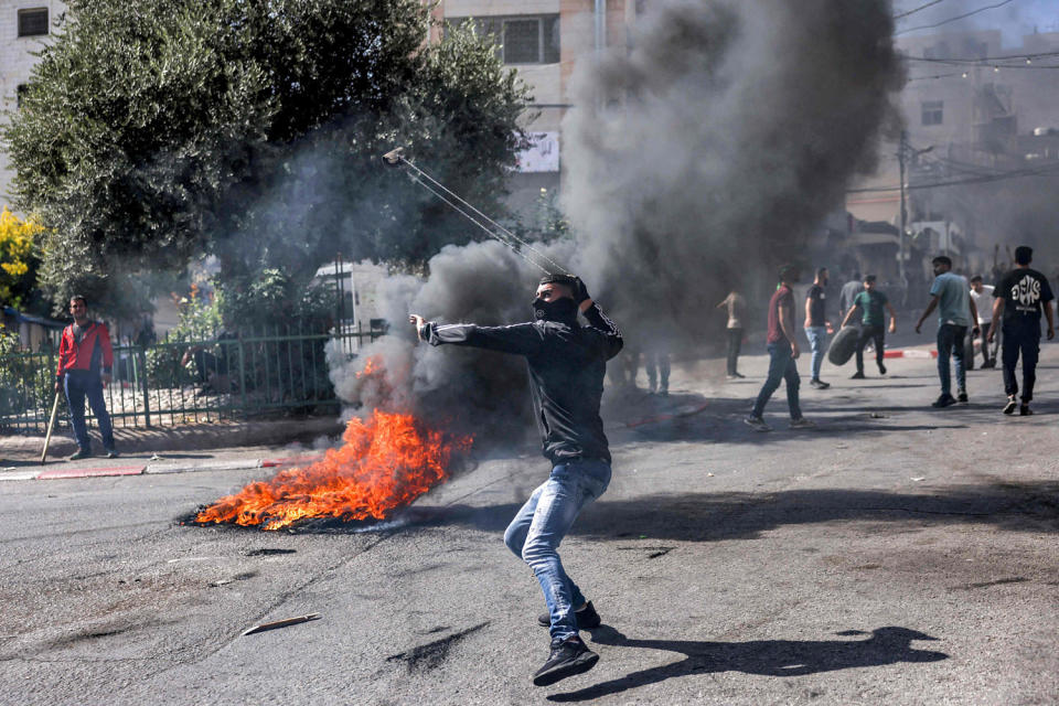 A Palestinian protester hurls back a tear gas canister with a sling during clashes with Israeli forces following a rally in solidarity with Gaza in Hebron in the occupied West Bank on Oct. 13, 2023. (Hazem Bader / AFP - Getty Images)