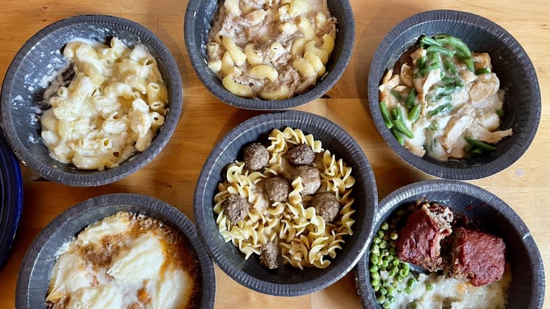 Six cooked microwave meals in plastic bowls