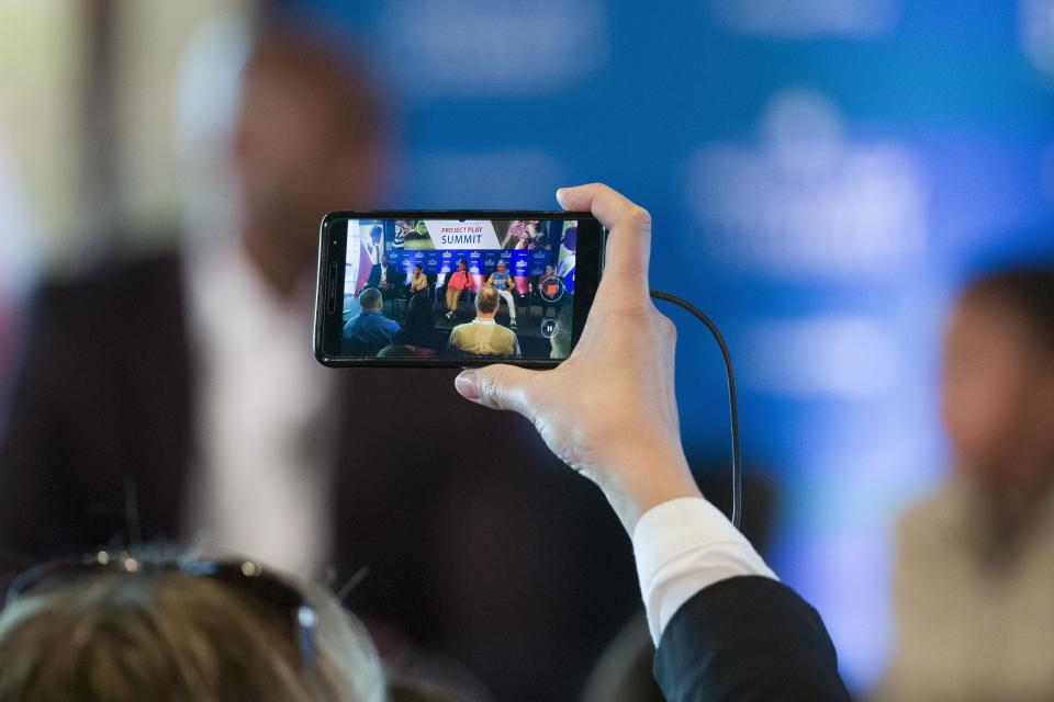 A person uses a cell phone to record former NBA basketball all-star Kobe Bryant speaking as he moderates a panel about youth sports during the Aspen Institute's Project Play Summit, Tuesday, Oct. 16, 2018 in Washington. (AP Photo/Alex Brandon)