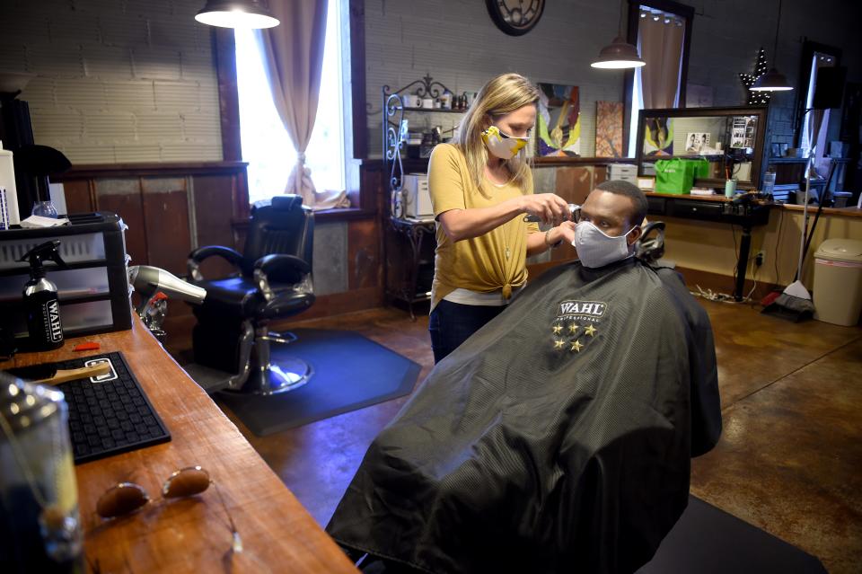 After opening following the coronavirus pandemic, Shelley Craft, owner of The Men's Refinery BarberSpa gives a haircut to Kenneth Gregory at her salon in Augusta, Ga., Friday morning April 23, 2020. 