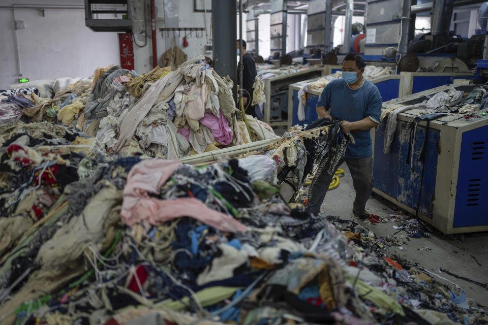 A worker feeds discarded textiles to a shredding machine at the Wenzhou Tiancheng Textile Company, one of China's largest cotton recycling plants in Wenzhou in eastern China's Zhejiang province on March 20, 2024. The recycling factory that repurposes discarded cotton clothes is trying to deal with the urgent waste problem. (AP Photo/Ng Han Guan)