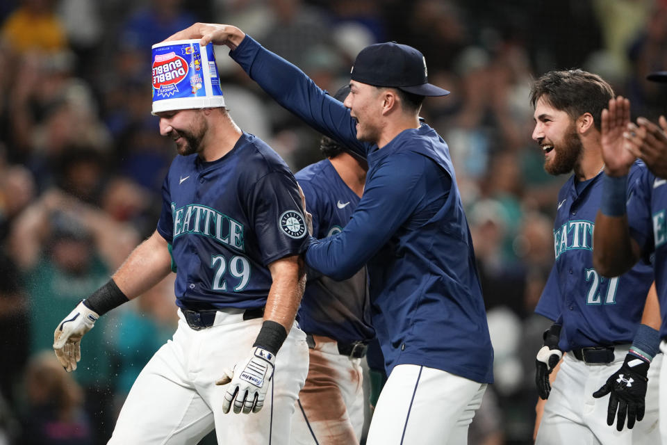 Seattle Mariners' Cal Raleigh has a bubble gum bucket put on his head by pitcher Bryan Woo as they celebrate Raleigh's game-winning grand slam for an 8-4 win against the Chicago White Sox in a baseball game, Monday, June 10, 2024, in Seattle. (AP Photo/Lindsey Wasson)