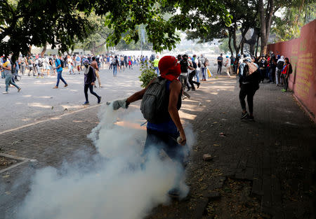 A demonstrator throws back a tear gas canister during clashes with security forces following a rally against the government of Venezuela's President Nicolas Maduro and to commemorate May Day in Caracas Venezuela, May 1, 2019. REUTERS/Carlos Garcia Rawlins