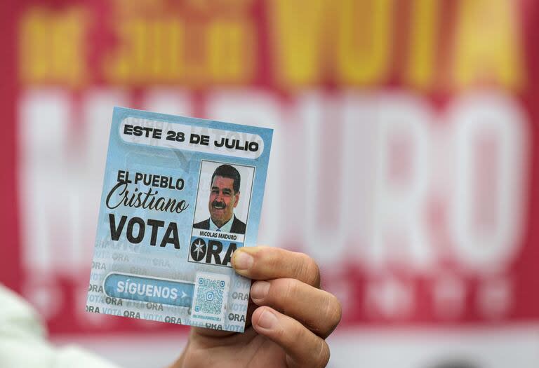 Un simpatizante de Maduro muestra un flyer del presidente venezolano (Photo by Yuri CORTEZ / AFP)