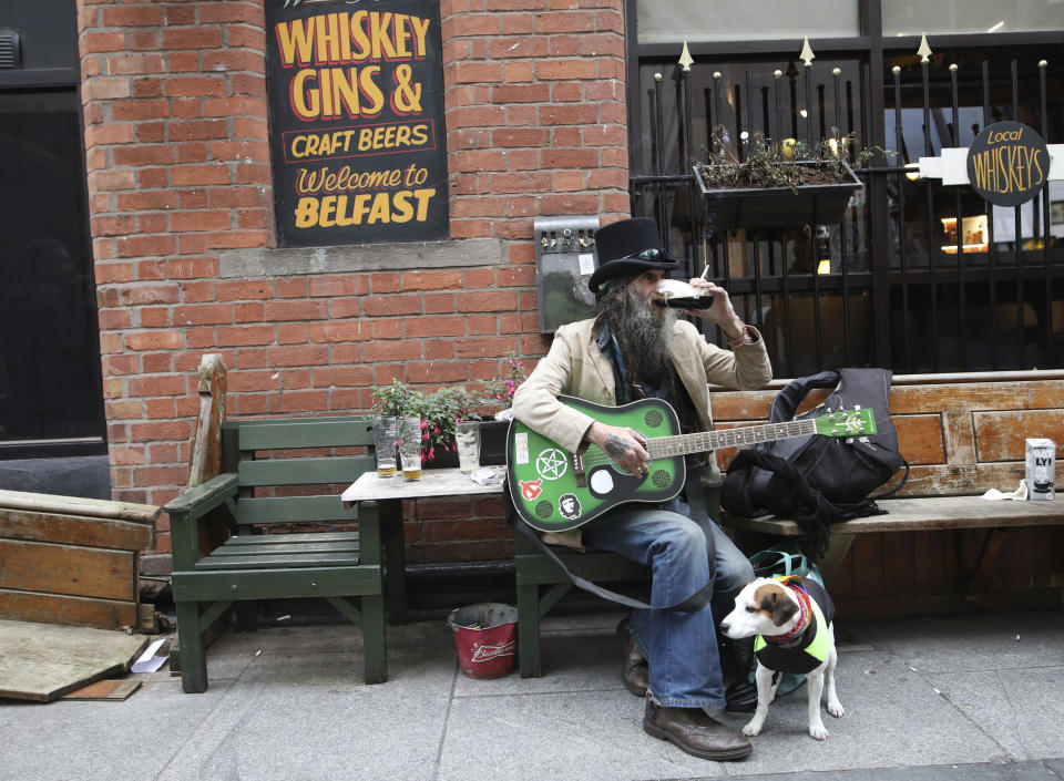 Kenny Robinson plays his guitar and enjoys a pint in Belfast, Northern Ireland, Friday, Oct 16, 2020. Northern Ireland has brought in restrictions to try and 'circuit break' the growing number of COVID-19 infections, they include -pubs closing from 1800, Friday, along with funerals and weddings limited to 25 people from for a period of 4 weeks. (AP Photo/Peter Morrison)