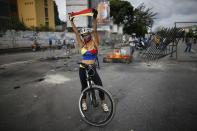 <p>A demonstrator astride her bicycle with her face painted in the Venezuelan national colors, holds a Venezuelan flag during a national sit-in against President Nicolas Maduro, in Caracas, Venezuela, Monday, May 15, 2017. (AP Photo/Ariana Cubillos) </p>