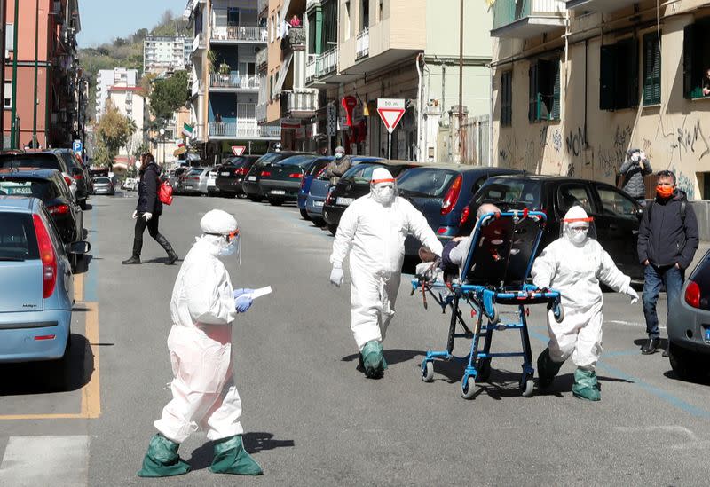 Foto del jueves de personal médico con trajes protectores trasladando a un paciente con coronavirus en Nápoles