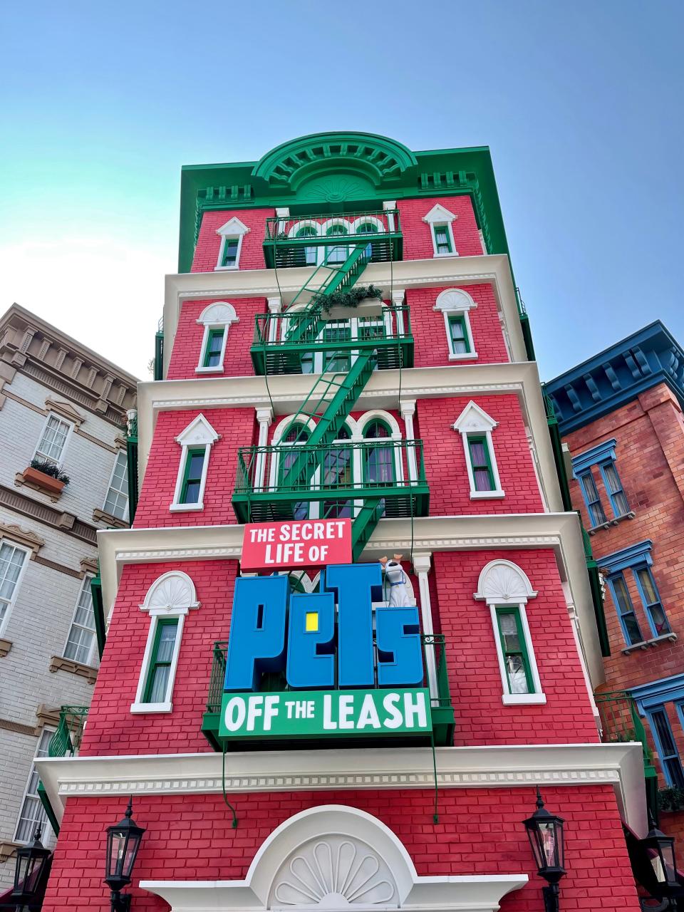 Secret life of pets off the leash ride entrnace with tall red building and green fire escapes up the side