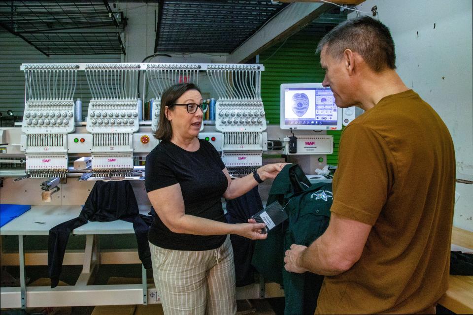 Cathie Nash, the president of Blue Line Innovations, speaks with embroidery department supervisor, Jim Kollar, in her West Palm Beach factory.