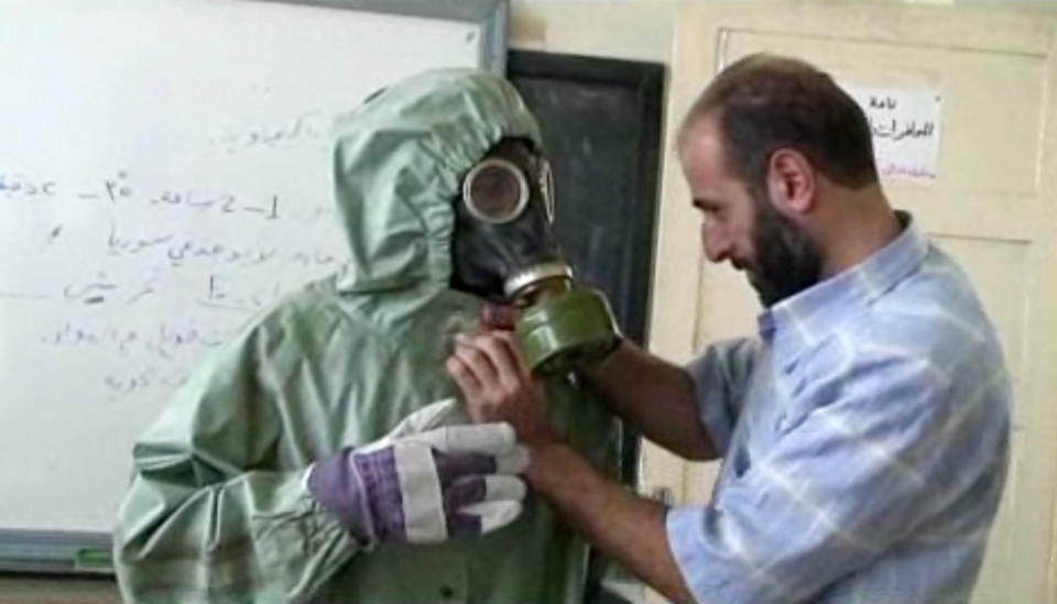 FILE - This file image made from an AP video posted on Wednesday, Sept. 18, 2013 shows a volunteer adjusting a gas mask and protective suit on a student during a classroom session a on how to respond to a chemical weapons attack in Aleppo, Syria. On Saturday, April 12, 2014 the Syrian government and rebel forces say poison gas has been used in a central village, injuring scores of people, while blaming each other for the attack. The main Western-backed opposition group, the Syrian National Coalition, says dozens of people were hurt in a poison gas attack Friday in the village of Kfar Zeita. State-run Syrian television on Saturday blamed members of the al-Qaida-linked Nusra Front for using chlorine gas at Kfar Zeita, killing two people and injuring more than 100. (AP Photo via AP video, File)