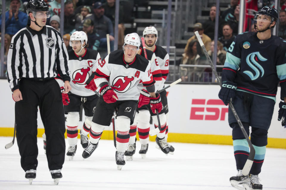 New Jersey Devils left wing Ondrej Palat (18) skates to the bench after scoring a goal, while Seattle Kraken left wing Andre Burakovsky, right, reacts during the first period of an NHL hockey game Thursday, Dec. 7, 2023, in Seattle. (AP Photo/Jason Redmond)