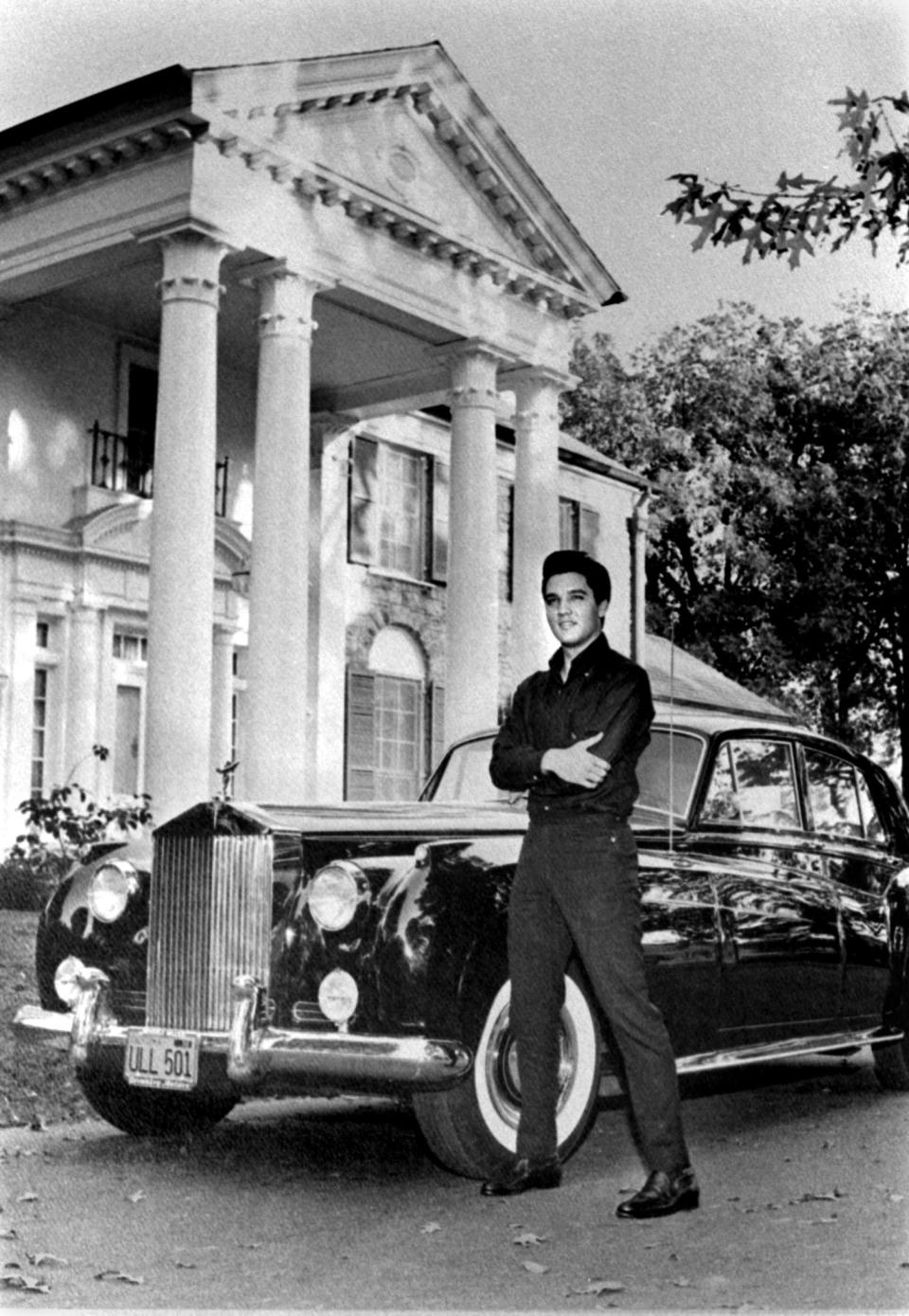 Elvis Presley poses in front of his Graceland home with his Rolls Royce in October 1960.