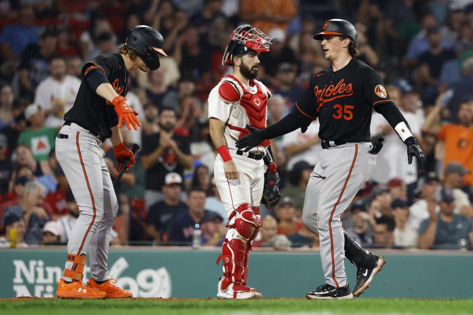 Baltimore Orioles' Adley Rutschman (35) celebrates after his solo home run with Gunnar Henderson, left, in front of Boston Red Sox catcher Connor Wong, center, during the eighth inning of a baseball game, Friday, Sept. 8, 2023, in Boston. (AP Photo/Michael Dwyer)
