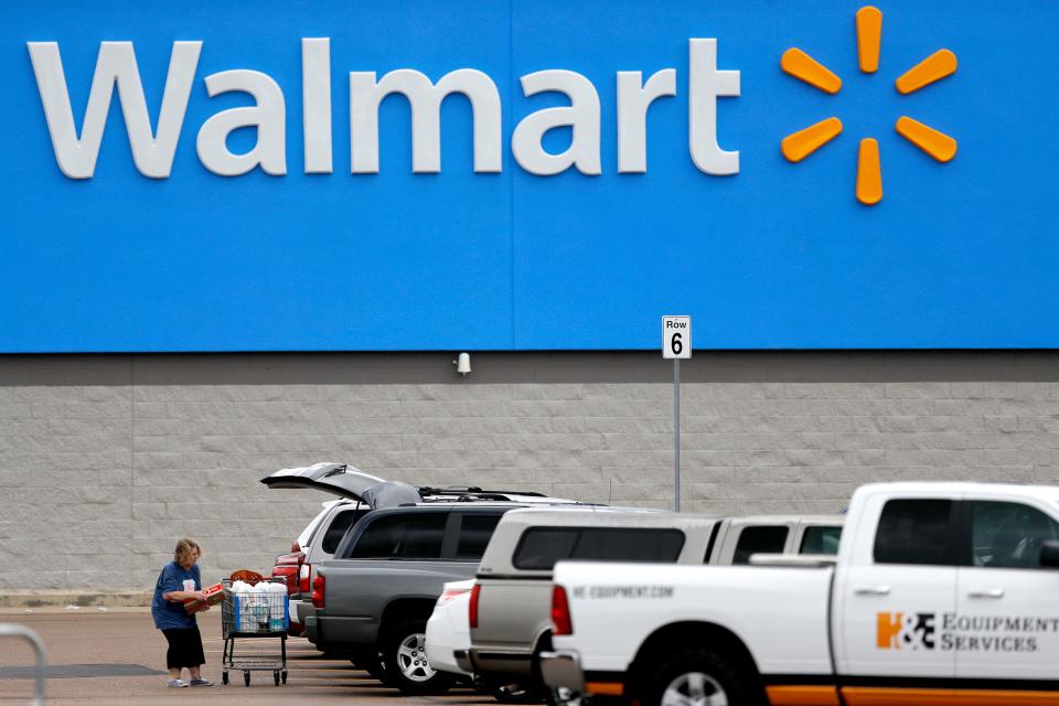 A customer loading shopping into the back of a car in the parking lot of a Walmart store