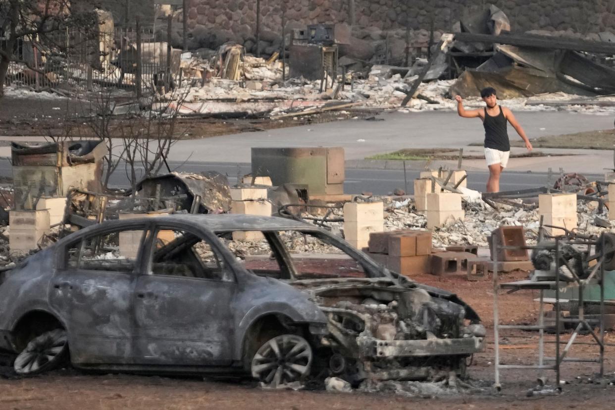 A young boy walks through wildfire wreckage Thursday, Aug. 10, 2023, in Lahaina, Hawaii.