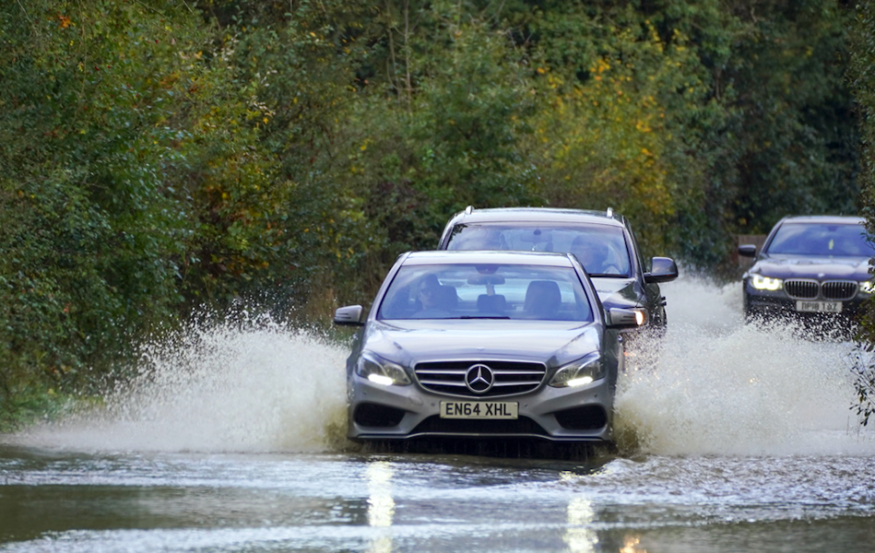 Cars drive through flood water on a road in Lingfield, Surrey, after southern England was hit overnight by heavy rain and strong winds from Storm Aurore. (PA(