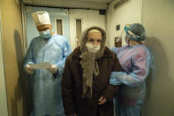 Two medical workers escort an elderly woman suffering from COVID-19 into a hospital in Kolomyia, western Ukraine, Tuesday, Feb. 23, 2021. After several delays, Ukraine finally received 500,000 doses of the AstraZeneca vaccine marketed under the name CoviShield, the first shipment of Covid-19 vaccine doses. The country of 40 million is one of the last in the region to begin inoculating its population. (AP Photo/Evgeniy Maloletka)