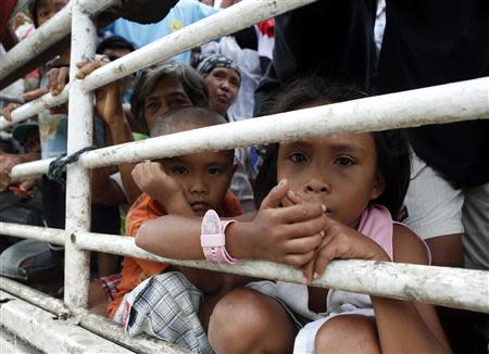 Children riding in a truck with other people made homeless by Super Typhoon Haiyan, look out of the vehicle as they wait to get relief goods at a government centre in Bogo, Cebu in the central Philippines November 17, 2013. REUTERS/Erik De Castro