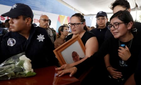 Relatives of a police officer, who was killed along other fellow police officers during an ambush by suspected cartel hitmen, react during an homage organised by the state government, in Morelia