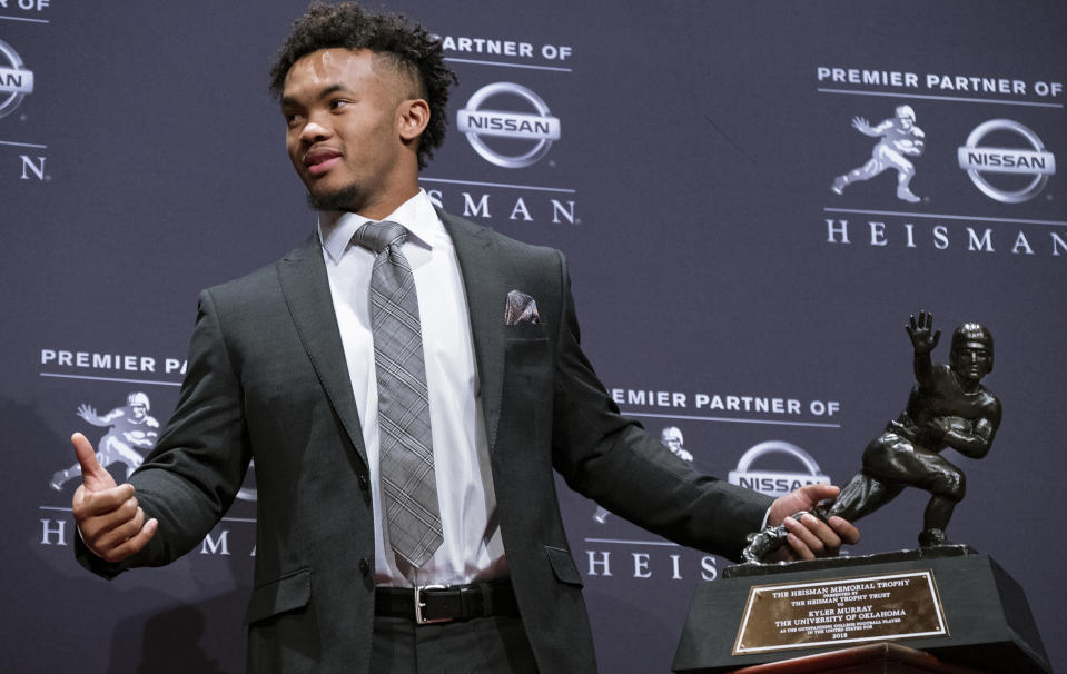 FILE - In this Dec. 8, 2018, file photo, Oklahoma quarterback Kyler Murray holds the Hesiman Trophy after winning the award in New York. Murray's locker remained empty on Monday, Feb. 11, 2019, in the spring training clubhouse of the Oakland Athletics, who say they are uncertain when or if the Heisman Trophy winner will report to the baseball team he signed with last summer. Billy Beane, Oakland’s executive vice president of baseball operation, said talks are continuing with Murray, who may drop baseball to pursue an NFL career. (AP Photo/Craig Ruttle, File)