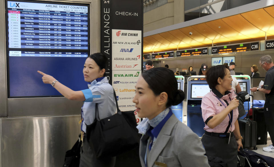 Flight attendants and travelers make their way through the Tom Bradley International Terminal at LAX on Wednesday, Aug. 30, 2023, in Los Angeles. With Labor Day weekend just days away, airports and roadways are expected to be busy as tens of thousands of Southern Californians travel out of town. (Dean Musgrove/The Orange County Register via AP)