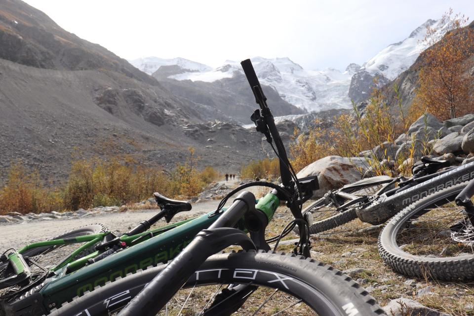 e-bike laying on its side next to a trail with a mountain glacier in the background