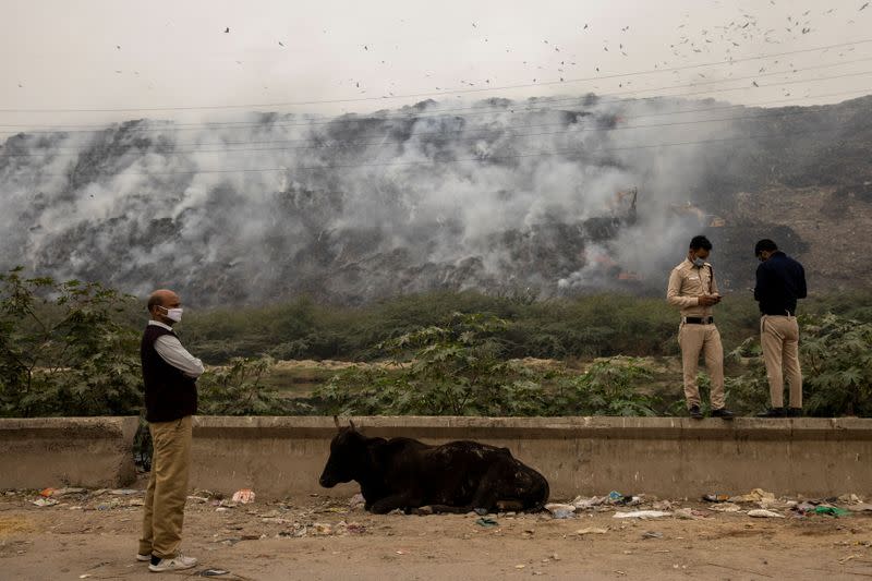 Members of Delhi government anti-pollution squad report the status of the fire as smoke billows from burning garbage at the Ghazipur landfill site in New Delhi