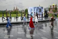 Models display a collection by a group of Russian designers of the Moscow Art-Industrial Institute, during the Fashion Week at Zaryadye Park with the Spasskaya Tower and St. Basil's Cathedral on the left in background near Red Square in Moscow, Russia, Tuesday, June 21, 2022. More than 100 shows are being held during the week that began Monday as well as scores of speakers who are noted names in the Russian fashion industry. (AP Photo/Alexander Zemlianichenko)