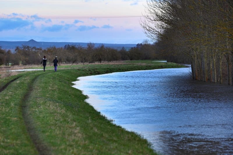 Two joggers on the Helme dyke near Moenchpfiffel-Nikolausrieth. The flood situation on the Helme and at the Kelbra reservoir remains tense. Heiko Rebsch/dpa