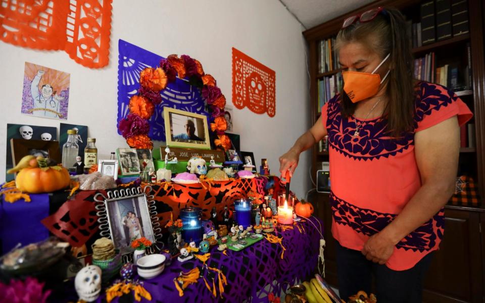 Rosario Martinez lights candles on a Day of the Dead altar for her husband - Eduardo Verdugo/AP