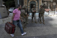 Lebanese army soldiers stand guard as a man flees his house after deadly clashes erupted nearby along a former 1975-90 civil war front-line between Muslim Shiite and Christian areas, in Ain el-Remaneh neighborhood, Beirut, Lebanon, Thursday, Oct. 14, 2021. Armed clashes broke out in Beirut Thursday during the protest against the lead judge investigating last year's massive blast in the city's port, as tensions over the domestic probe boiled over. (AP Photo/Bilal Hussein)