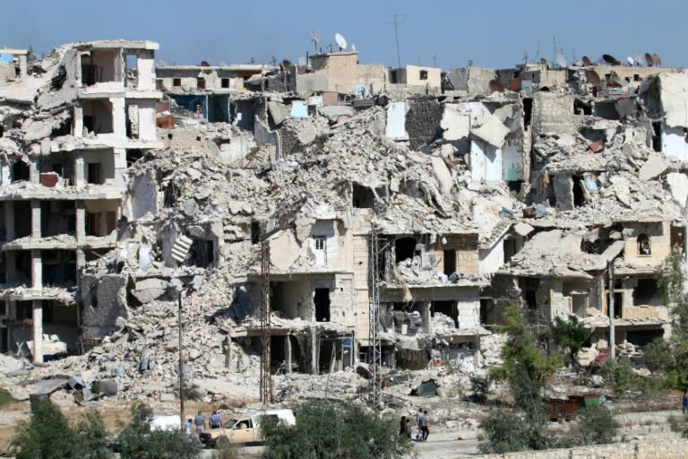 Syrians walk past heavily damaged buildings in the neighbourhood of Bani Zeid, on Aleppo's northern outskirts on July 29, 2016