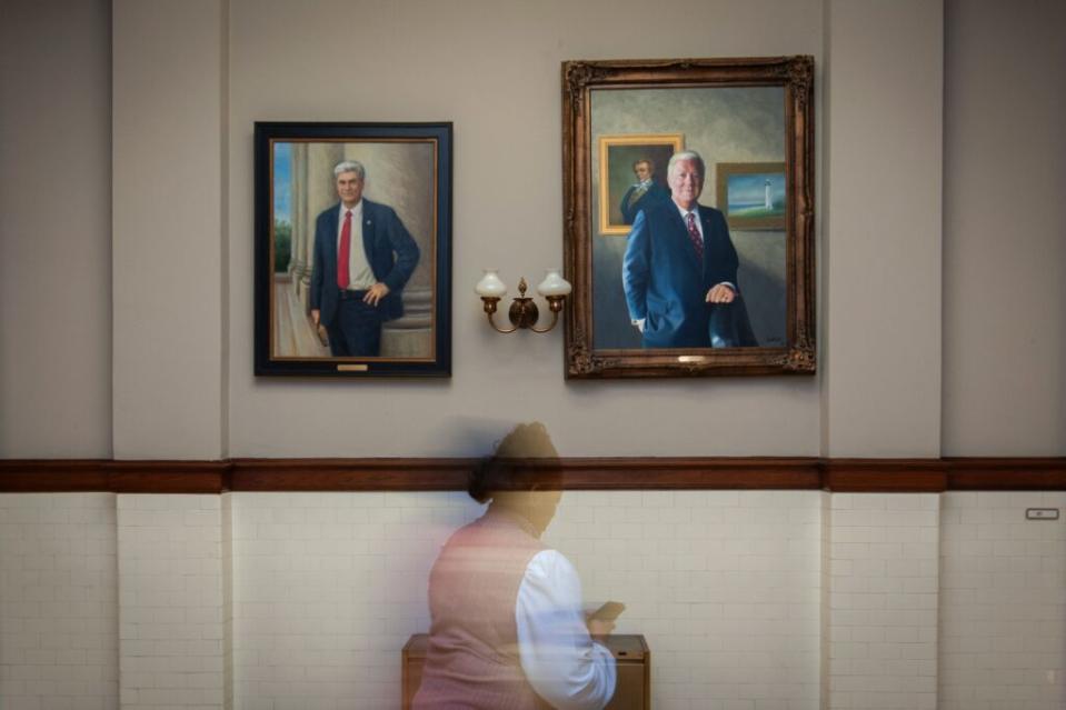 A blurry woman between paintings of a man in a suit