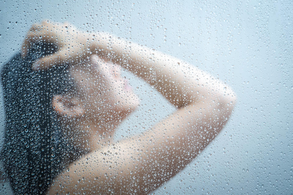 Women showering in the shower room close up with a water drop on glass door.