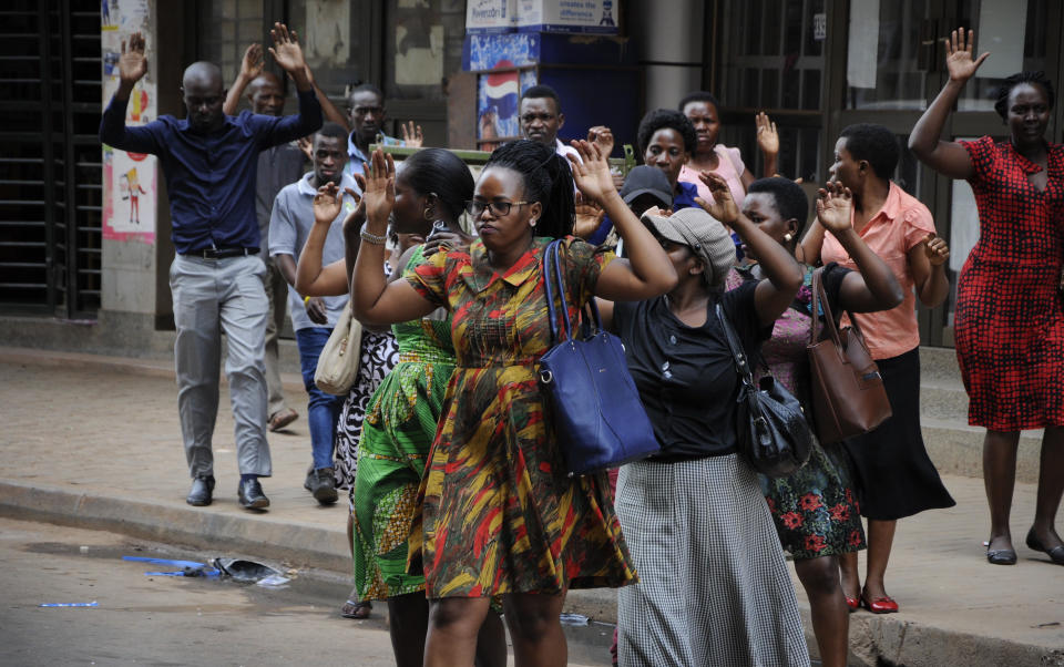 Residents are ordered out of a building with their hands in the air as security forces pursue protesters in Kampala, Uganda, Monday, Aug. 20, 2018. Ugandan police fired bullets and tear gas to disperse a crowd of protesters demanding the release of jailed lawmaker, pop star, and government critic Kyagulanyi Ssentamu, whose stage name is Bobi Wine. (AP Photo/Ronald Kabuubi)