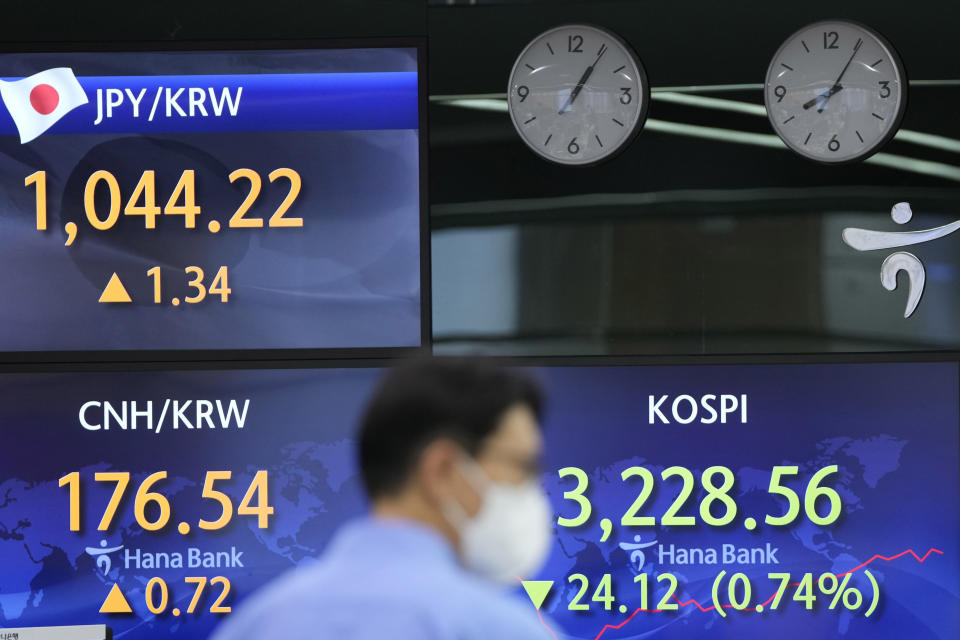 A currency trader walks by the screens showing the Korea Composite Stock Price Index (KOSPI), right, and the foreign exchange rates at the foreign exchange dealing room in Seoul, South Korea, Friday, July 9, 2021. Shares were mostly lower in Asia on Friday after stocks pulled back from their recent record highs on Wall Street as bond yields fell and investors turned cautious. (AP Photo/Lee Jin-man)