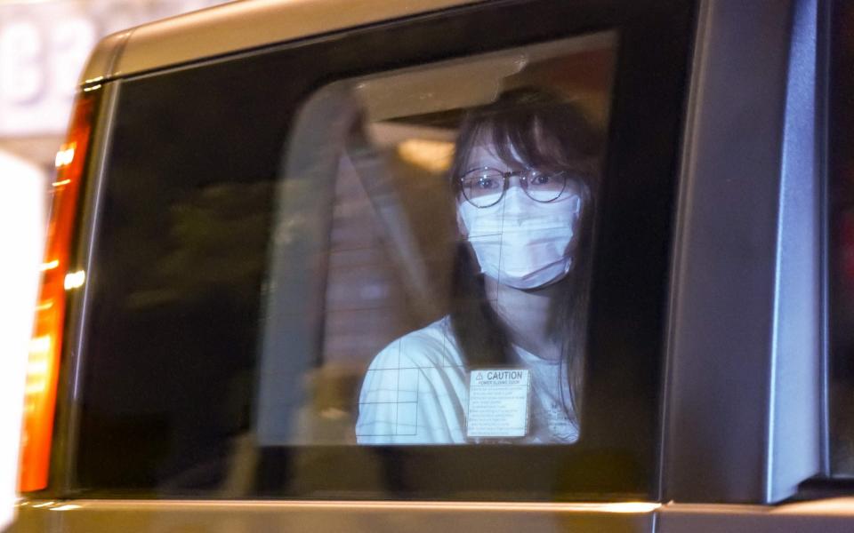 Prominent Hong Kong democracy activist Agnes Chow looks out of a car window while being driven away by police from her home after she was arrested under the new national security law in Hong Kong - AFP