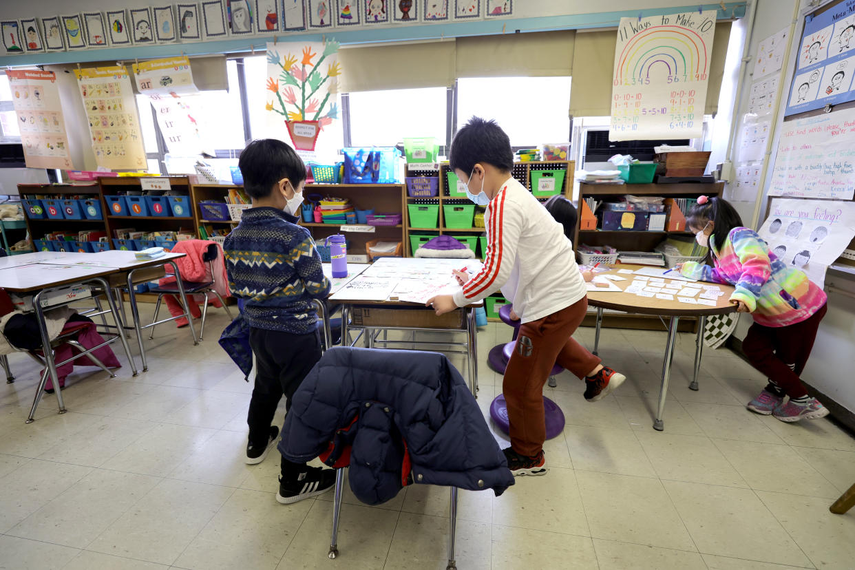 Elementary school students wearing masks tend to an assignment in class.