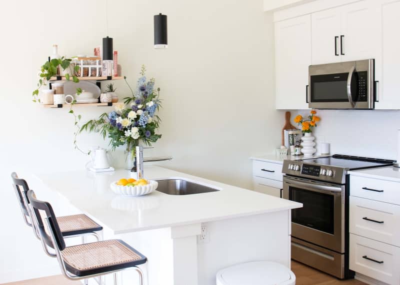 A white kitchen with bar stools and open shelving