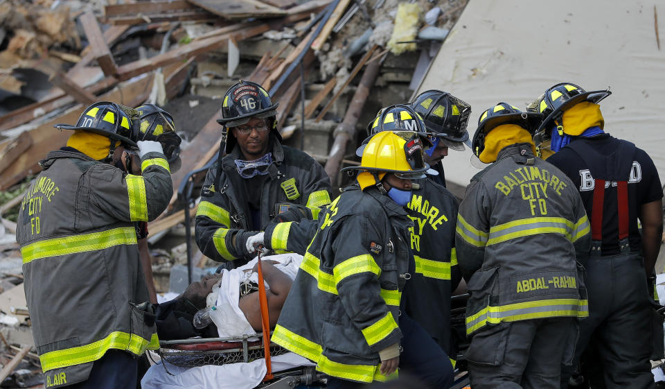 Baltimore City Fire Department carries a person out from the debris after an explosion in Baltimore on Monday, Aug. 10, 2020. Baltimore firefighters say an explosion has levelled several homes in the city. (AP Photo/Julio Cortez)