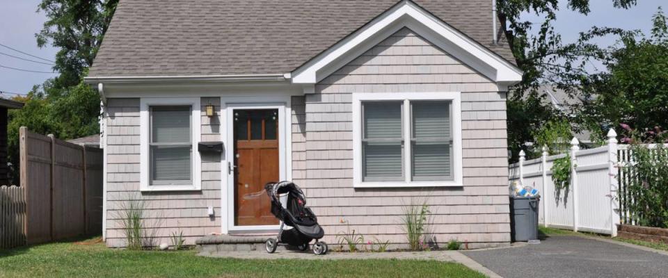 Suburban Bungalow Home with Baby Carriage Parked on Front Yard Lawn Sunny Residential Neighborhood House USA