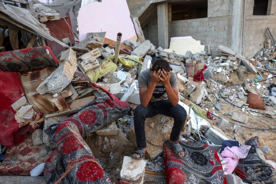 A Palestinian youth reacts as he sits on the rubble of a destroyed home following an Israeli military strike on the Rafah refugee camp in Gaza.