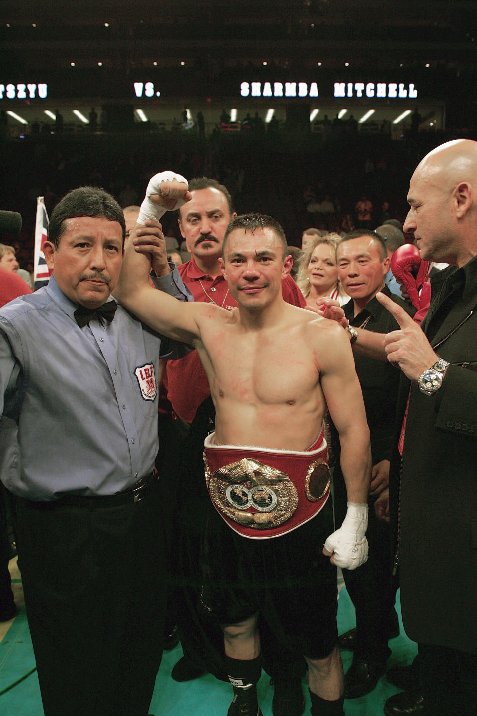 Kostya Tszyu celebrates with his hand raised in the ring.