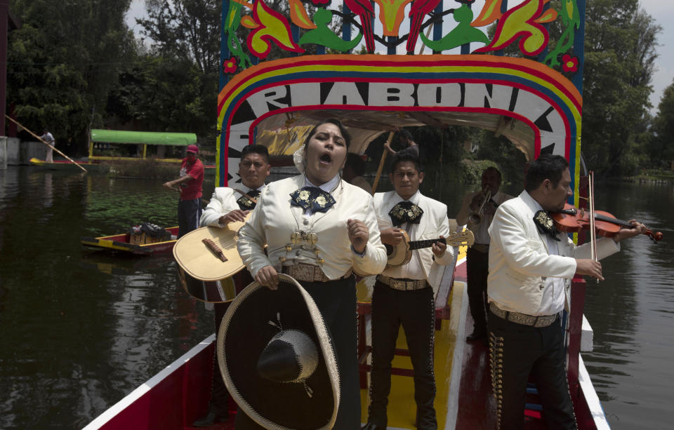 Mariachis perform on one of the painted wooden boats, known as a trajinera, popular with tourists that ply the water canals in the Xochimilco district of Mexico City, after all activities had been on pause for the past six months due to the COVID-19 pandemic. (AP Photo/Marco Ugarte)