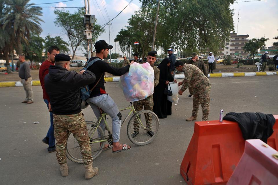 Iraqi security forces search people heading to Tahrir Square where ongoing anti-government protests are taking place in Baghdad, Iraq, Sunday, Dec. 8, 2019. Gunmen in cars opened fire Friday in Baghdad's Khilani square, killing dozens of people. (AP Photo/Khalid Mohammed)